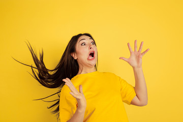 Astonished, crazy. Caucasian woman's portrait isolated on yellow studio background. Beautiful female brunette model in casual style. Concept of human emotions, facial expression, sales, ad, copyspace.