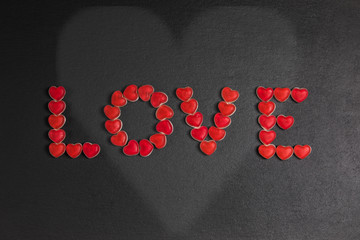 Love aus Bonbons auf Schieferplatte mit Herz.