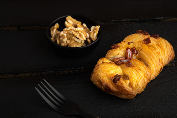 small puff pastry cake with nuts on black wooden background