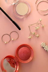 Beauty products and fashionable accessories on pale pink background: blush, mascara, eyeliner, lipstick,k rings, hoop earrings, beret and gypsophila flowers. Top view.