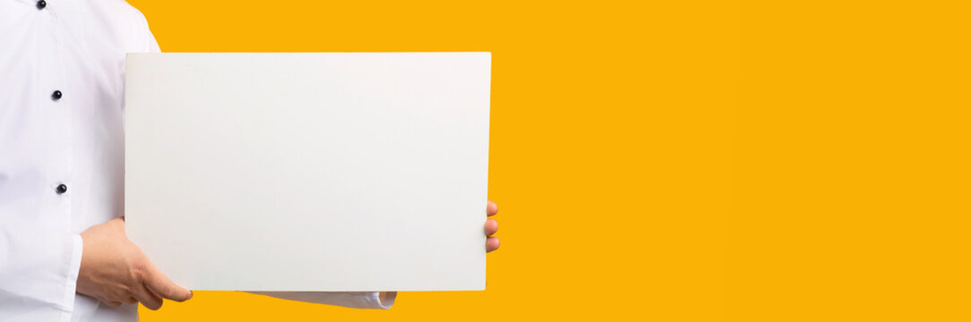 Unrecognizable Chef Holding Empty White Board Over Yelllow Background, Mockup