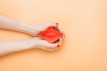 small red paper boat in female palms. conceptual abstract image of the vagina