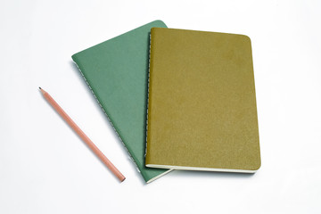Top view of closed stitch blank recycled paper cover notebook with pencil on white background.
