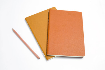 Top view of closed stitch blank recycled paper cover notebook with pencil on white background.