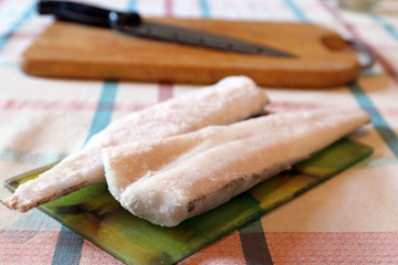 Several slices of frozen fish on glass cutting board