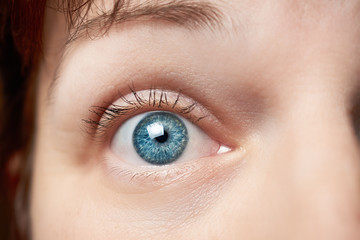 The wide open blue eye of a young woman: a concept of surprise and close observation