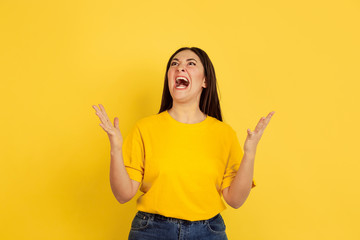 Angry screaming. Caucasian woman's portrait isolated on yellow studio background. Beautiful female brunette model in casual style. Concept of human emotions, facial expression, sales, ad, copyspace.