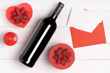 Heart, candle, wine bottle, envelope with letter on white wooden surface. Valentine's day concept. Flat lay, top view, from above