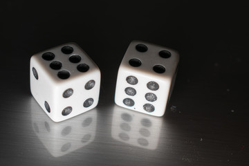 Closeup of a pair of dice on a reflective surface, with winning numbers and reflection bellow them.