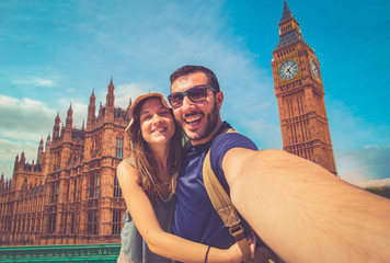 Tourist couple travelling in London taking selfie using smart phone with famous Big Ben tower on...