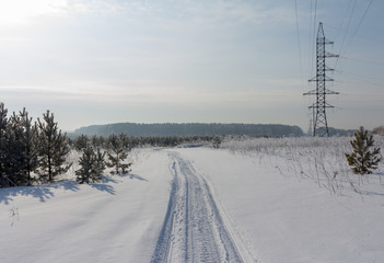 Fototapeta premium snowmobail trail at field covered by snow