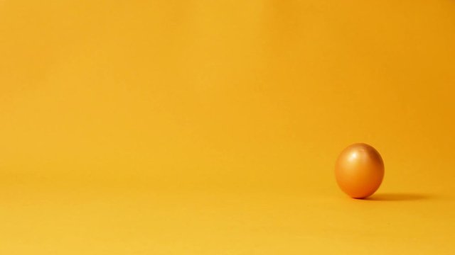 Chicken gold easter egg spinning on yellow background. Happy Easter Concept