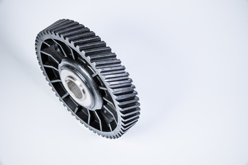 Black polymer gear camshaft with metal base. New spare part for an internal combustion engine on a gray background