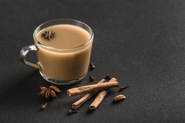 Popular Asian warming drink masala tea in a clear glass cup with coriander, cinnamon and rose stem...
