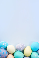 Colorful Easter eggs dyed by colored water with beautiful pattern on a pale blue background, design concept of holiday activity, top view, full frame.