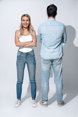 Cool attitude. Full length of beautiful young couple. girl looking to the camera while bou looking back against grey background