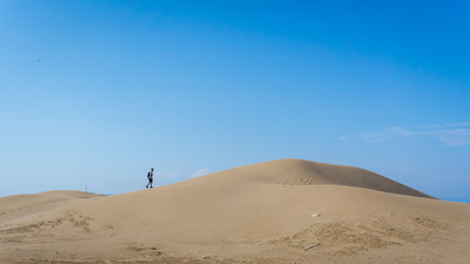 Fototapeta na wymiar adventurer walking on a dune in a desert