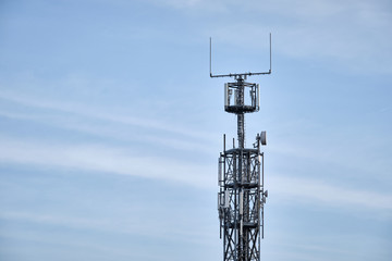 Close-up of lattice mast with base station for mobile communications against blue sky with clouds. Seen in Germany in February