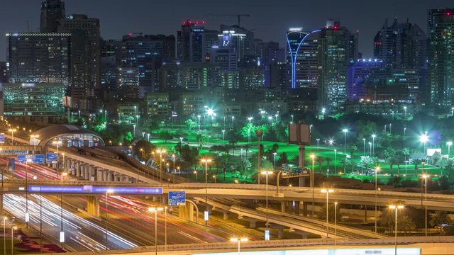 Dubai Golf Course with a cityscape of Gereens and tecom districts at the background aerial night timelapse. Traffic on sheikh zayed road with junction