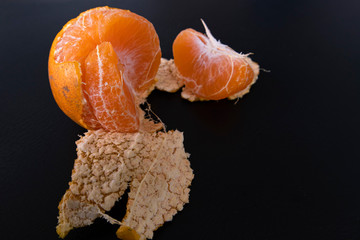 Healthy fresh orange.Design isolated on black. Healthy diet concept. Peeled oranges are placed on black floor. Concept comparison of differences between people with orange petals in same ball value