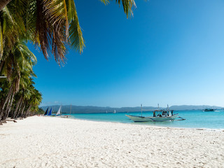 Beautiful Boracay - Philippines tropical island beach with palm tree, boat and tranquil blue water on clear day sky