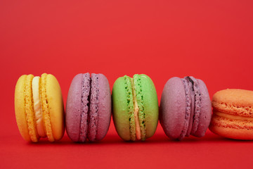 yellow, purple, green round baked macarons cakes on a red background