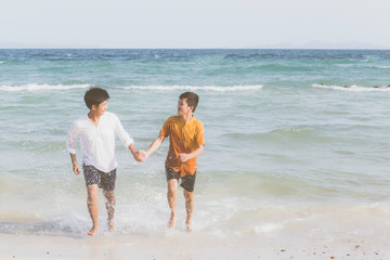 Homosexual portrait young asian couple running with cheerful together on beach in summer, asia gay going tourism for leisure and relax with happiness in vacation at sea, LGBT legal concept.