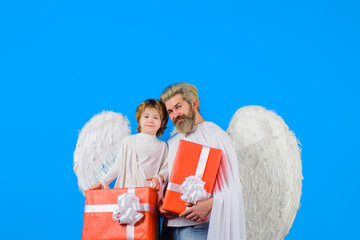 Cute angel. Little angel boy gives father gift. Happy father in angel costume with little son angel...