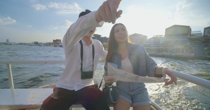 Young couple traveler enjoying a boat trip. Young Asian Girl and boyfriend travelling by boat in Chao Phraya river exploring Bangkok, Thailand.