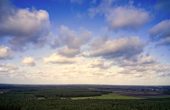 Blue sky with white clouds over the cultural landscape in the north of Germany with forests, meadows and fields, aerial view with the drone