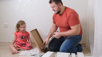 Dad and daughter collect furniture from chipboard. Dad and girl collect home furniture together.