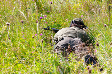 Two people playing airsoft hid in ambush behind fence