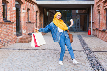 Sale and buying concept - Happy arab muslim girl with shopping bags after mall