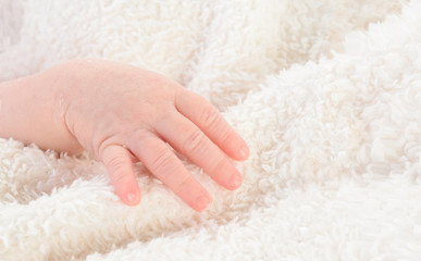 Fototapeta na wymiar Mano de bebé recién nacido sobre manta blanca