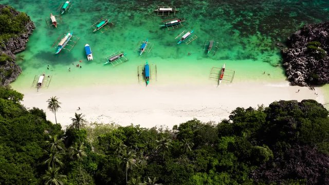 Tropical island with sandy with tourists and blue sea, aerial view. Matukad Island, Caramoan Islands, Philippines. 