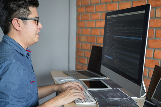Young Professional programmer working at developing programming and website working in a software develop company office, writing codes and typing data code, Programming with HTML, PHP and javascript