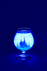 Glowing glass goblet with magical landscape in water