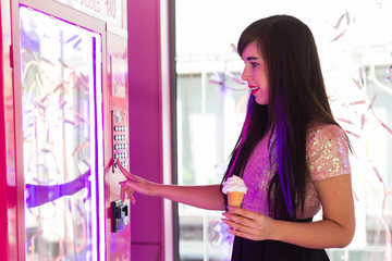 Pretty young woman using a modern beverage vending machine. Her hand is placed on the dial pad.