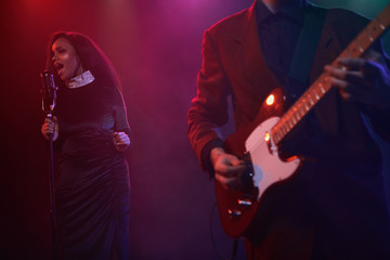 A jazz singer and guitarist perform on stage.