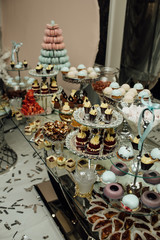 Delicious wedding reception candy bar dessert table full with cakes and sweets 