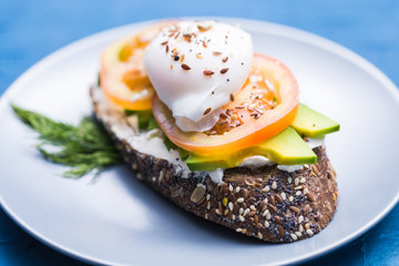 Sandwich with smoked salmon, egg and avocado on blue background. Concept for healthy nutrition.