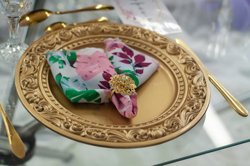 Table setting with a golden plate and an elegant napkin