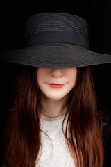 Beautiful woman portrait with a big hat. Vintage look. Fashion makeup. The hat covers part of the face