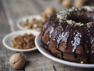 Festive homemade cakes. Round chocolate muffin, large biscuit or cake with chocolate icing on an ancient wooden background. Place for text, side view.