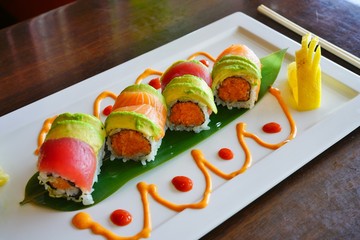 A plate of avocado, tuna and salmon sushi roll with pickled ginger and wasabi at a Japanese restaurant