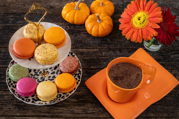 Many colorful macaroons on the table with coffee and hot chocolate