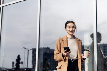 Head and shoulders slow motion portrait of beautiful and confident young woman in formal suit standing outdoors, looking at camera and smiling