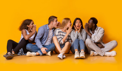 Group of multiracial friends gossiping over yellow background
