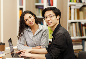Smiling multicultural couple learning at modern library