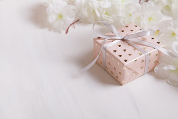 International Women's Day. Valentine's Day background. Gift box with ribbon and white flowers on a natural marble background.. Valentine's day and birthday concept.